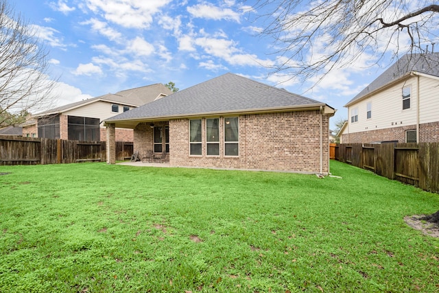 back of property featuring a shingled roof, brick siding, a yard, and a patio