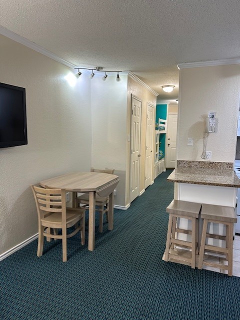 6102 Seawall Blvd Unit 128, Galveston, TX 77551 - dining space featuring a textured ceiling, dark colored carpet, and crown molding