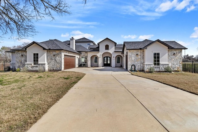 french country inspired facade featuring a garage and a front lawn