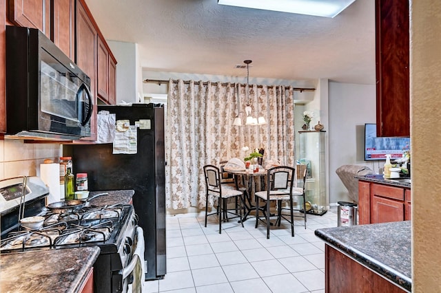 kitchen featuring decorative light fixtures, dark stone countertops, light tile patterned floors, gas range, and a textured ceiling