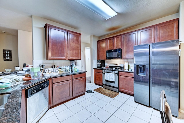 kitchen with dark stone countertops, light tile patterned floors, decorative backsplash, and stainless steel appliances