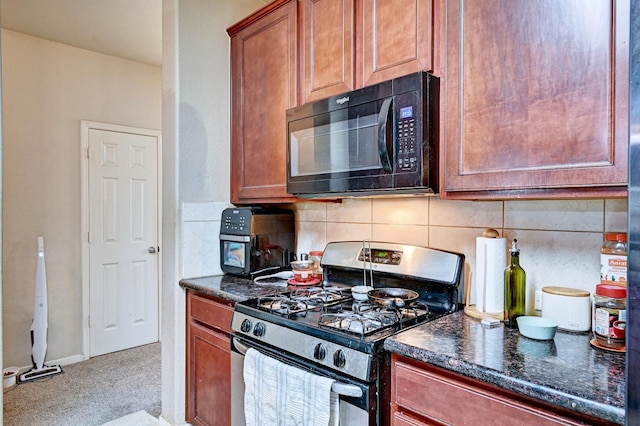 kitchen featuring dark stone countertops, stainless steel gas range, and backsplash