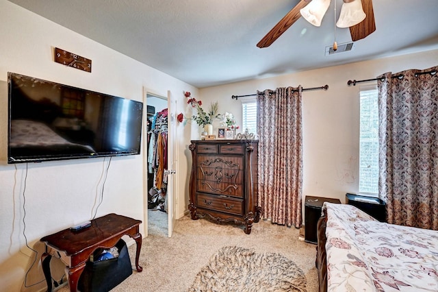 carpeted bedroom featuring a spacious closet, a closet, and ceiling fan