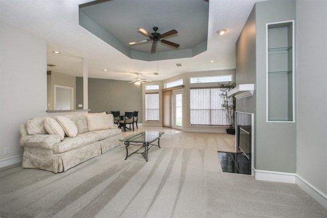 living room with light carpet, a raised ceiling, and ceiling fan