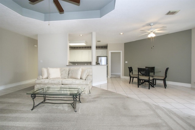 living room featuring ceiling fan, a raised ceiling, and light tile patterned floors