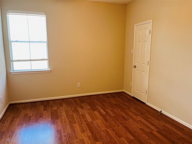 spare room featuring dark wood-type flooring and plenty of natural light