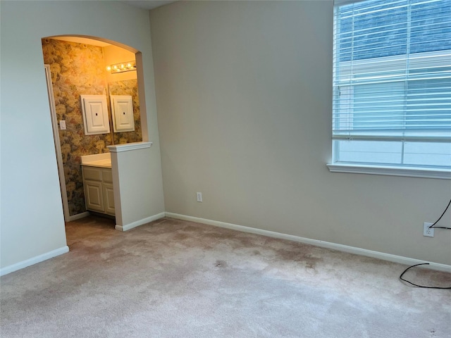 unfurnished bedroom with ensuite bathroom and light colored carpet