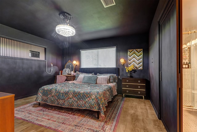 bedroom featuring visible vents, a notable chandelier, and wood finished floors