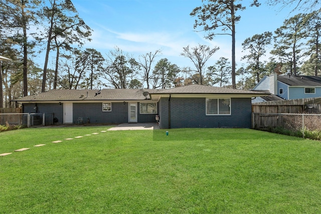 rear view of property featuring a patio, brick siding, a lawn, and a fenced backyard