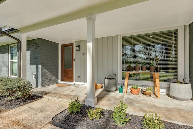 view of exterior entry featuring a porch and brick siding