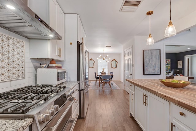 kitchen with butcher block countertops, wood finished floors, exhaust hood, visible vents, and white cabinetry