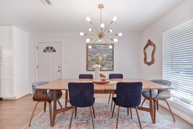 dining area with a chandelier, visible vents, and light wood-style floors