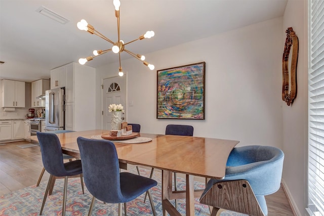 dining area featuring baseboards, light wood-style flooring, visible vents, and a notable chandelier