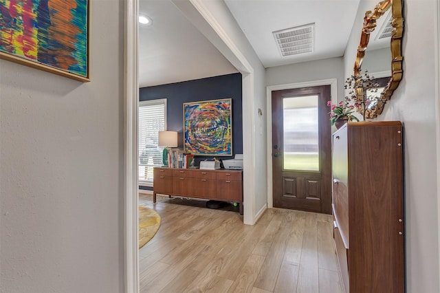 foyer with light wood-style flooring, visible vents, and baseboards