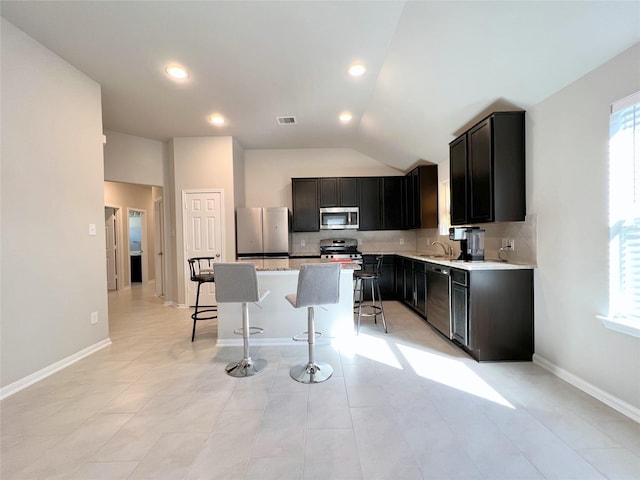 kitchen featuring tasteful backsplash, a kitchen breakfast bar, a center island, stainless steel appliances, and a healthy amount of sunlight