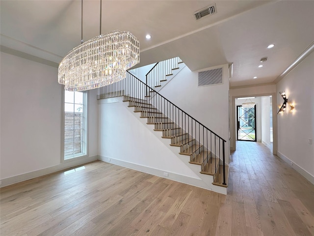 interior space with an inviting chandelier, crown molding, and hardwood / wood-style floors