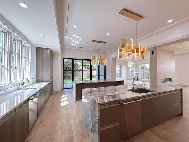 kitchen featuring sink, stainless steel dishwasher, hanging light fixtures, and a spacious island