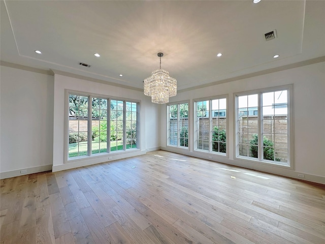 unfurnished room featuring an inviting chandelier, light hardwood / wood-style flooring, and ornamental molding