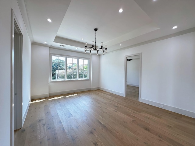 empty room featuring a tray ceiling and light wood-type flooring