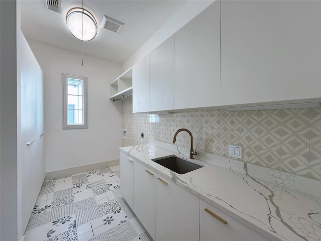 kitchen with white cabinetry, light stone countertops, sink, and decorative backsplash