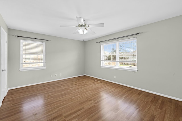 empty room with a healthy amount of sunlight, hardwood / wood-style floors, and ceiling fan