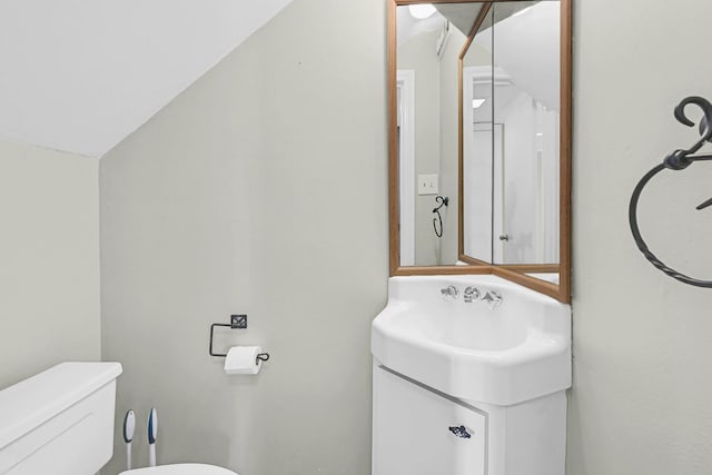 bathroom with lofted ceiling, vanity, and toilet