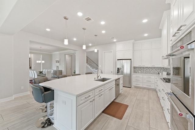 kitchen with white cabinetry, appliances with stainless steel finishes, a kitchen island with sink, and backsplash