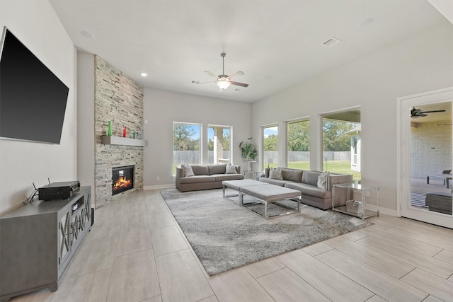 living room featuring a stone fireplace and ceiling fan