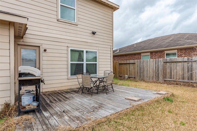 wooden terrace featuring a yard and a grill