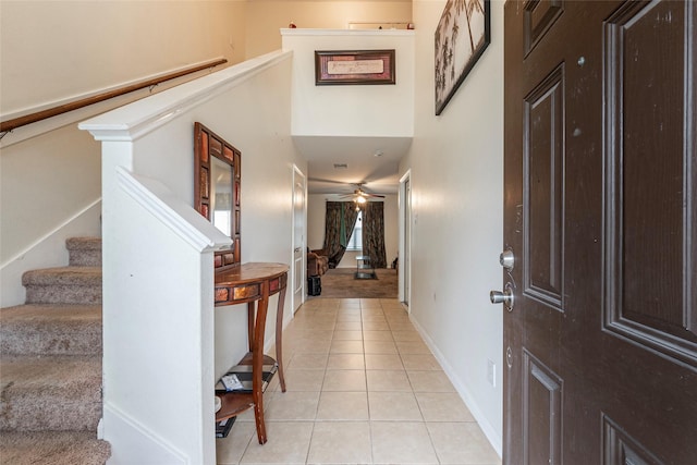 foyer entrance with a towering ceiling, light tile patterned floors, and ceiling fan