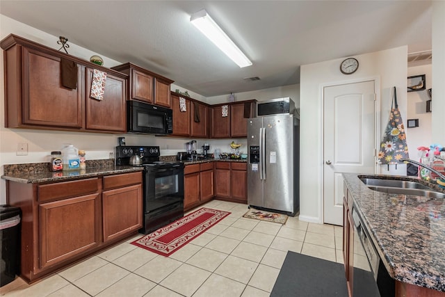 kitchen with light tile patterned flooring, sink, dark stone countertops, and black appliances