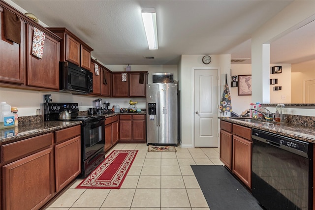 kitchen featuring sink, a textured ceiling, light tile patterned floors, dark stone countertops, and black appliances