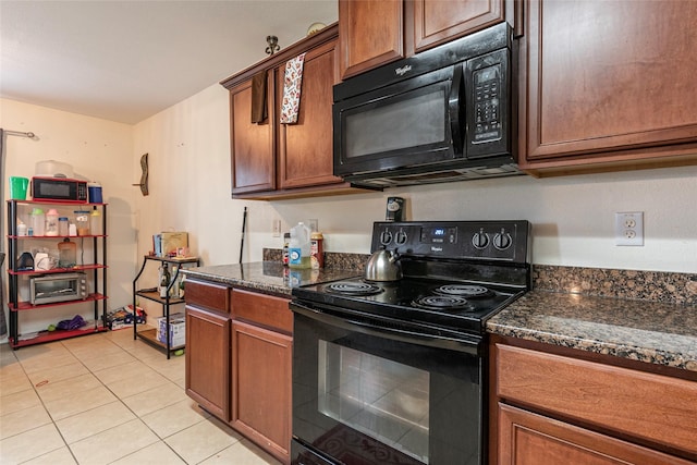 kitchen featuring black appliances, dark stone counters, and light tile patterned flooring