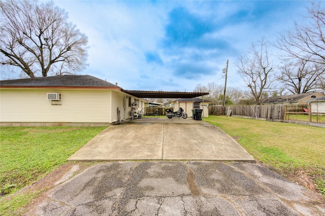 ranch-style home featuring a carport, a wall unit AC, and a front lawn