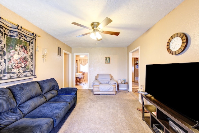 carpeted living room with ceiling fan and a textured ceiling