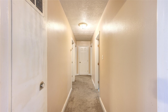 corridor featuring light colored carpet and a textured ceiling