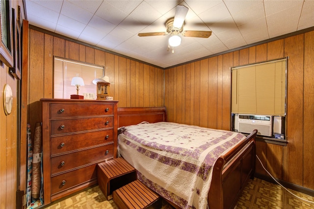 bedroom with ornamental molding, cooling unit, ceiling fan, and wood walls