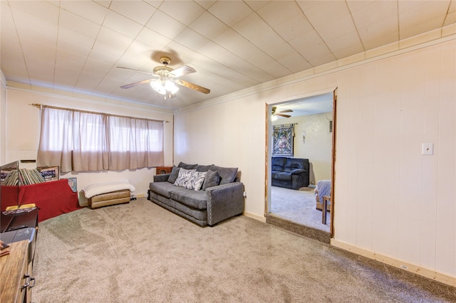 carpeted living room with ceiling fan and ornamental molding