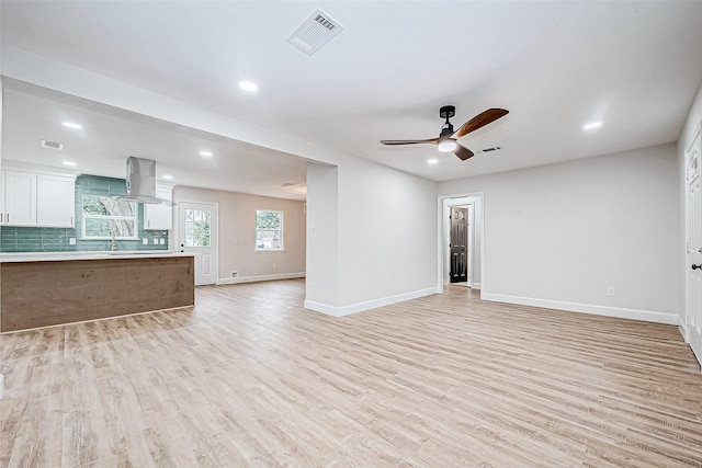 unfurnished living room featuring sink, ceiling fan, and light wood-type flooring