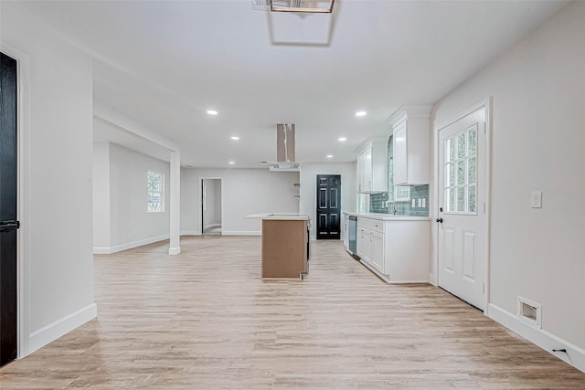 kitchen with a kitchen island, tasteful backsplash, white cabinetry, light hardwood / wood-style floors, and wall chimney range hood