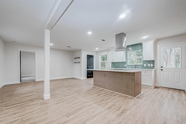 kitchen with white cabinetry, a kitchen island, island range hood, and light hardwood / wood-style flooring