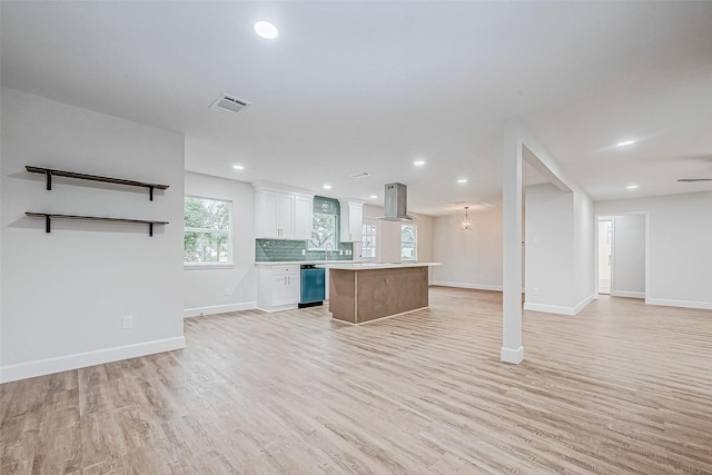 kitchen with white cabinetry, light wood-type flooring, dishwasher, a kitchen island, and backsplash