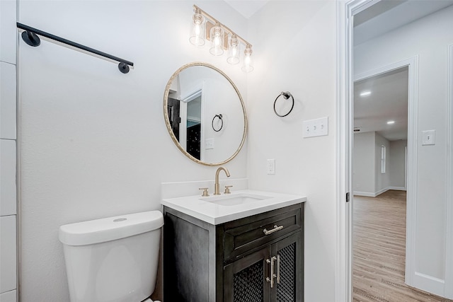 bathroom with vanity, toilet, and hardwood / wood-style floors