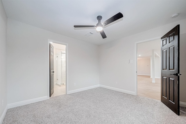 unfurnished bedroom featuring ensuite bathroom, light colored carpet, and ceiling fan