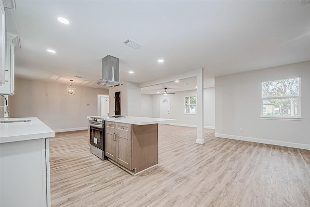 kitchen with stainless steel electric range oven, a kitchen island, pendant lighting, island exhaust hood, and light hardwood / wood-style flooring