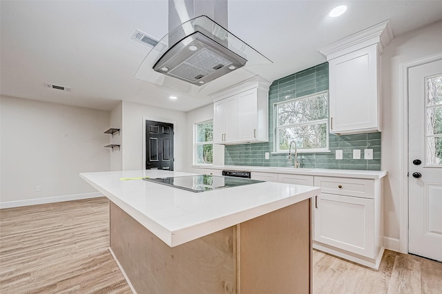 kitchen with sink, a center island, tasteful backsplash, white cabinets, and black electric cooktop