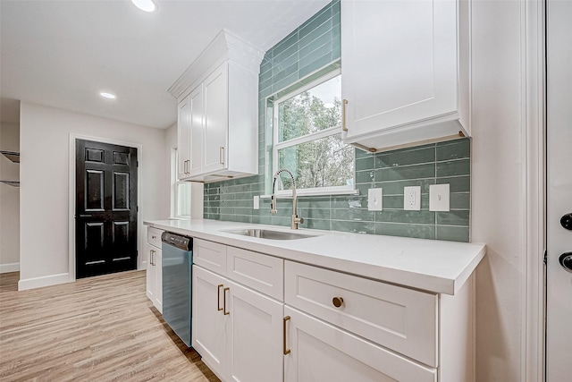 kitchen featuring sink, white cabinetry, tasteful backsplash, light wood-type flooring, and stainless steel dishwasher