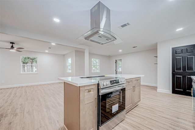 kitchen with stainless steel electric range oven, island range hood, a center island, light hardwood / wood-style floors, and light brown cabinets