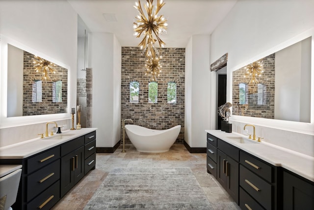 bathroom with a bathing tub, vanity, an inviting chandelier, and brick wall