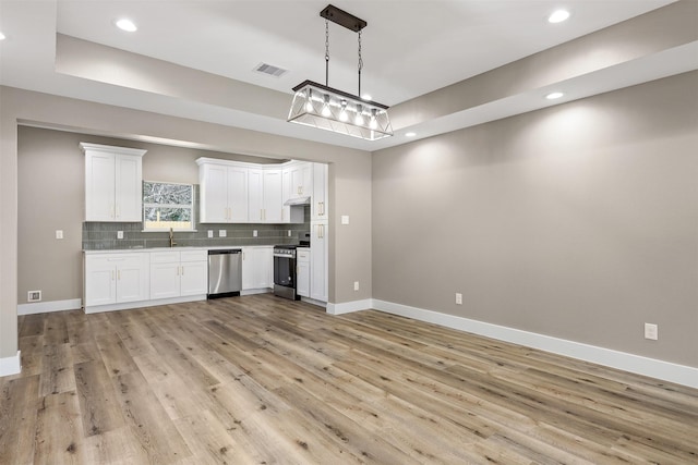 kitchen featuring white cabinetry, decorative light fixtures, light wood-type flooring, stainless steel appliances, and decorative backsplash
